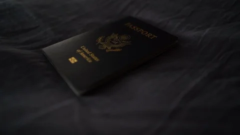 Track Right Light Hitting an American Passport on Bed Stock Footage 96044407