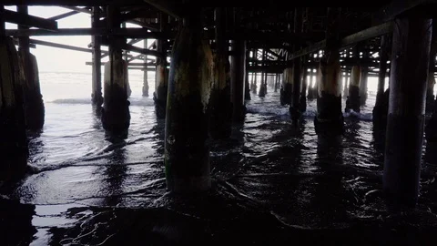 Track Right Old Weathered Posts and Water Rolling in Under Pier Stock Footage 96043494