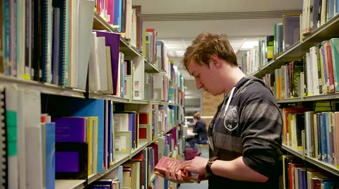 Track in on a Student Picking out a Book Stock Footage 61638804