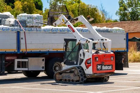 Tracked loader unloading materials from a parked truck Stock Photos