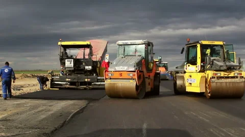 Tracked paver laying fresh asphalt pavement, time lapse Stock Footage