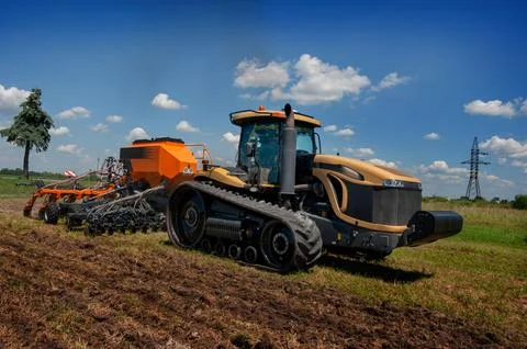A tracked tractor pulls a precision seed drill, movement in operation Stock Photos