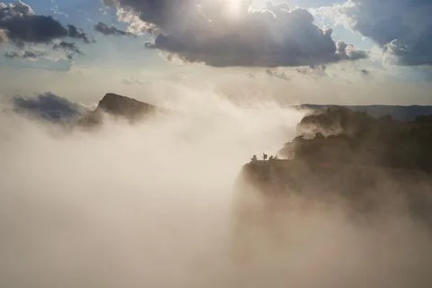 Tracker stands on the top of a mountain in the light of the sun and clouds. Stock Photos