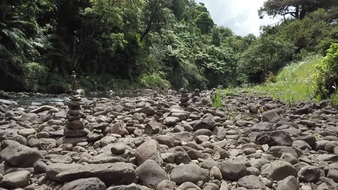 TRACKING 60FPS SLOMO between stacks of balancing pebbles, in the rain Stock Footage 147331090