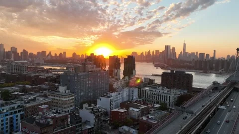 Tracking aerial over Brooklyn rooftops toward Manhattan skyline at sunset Vídeo Stock 344591663