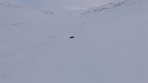 Tracking Aerial Pass Over Snowmobile Rider Turning Symbolizing Arctic Adventure Stock Footage 345328456