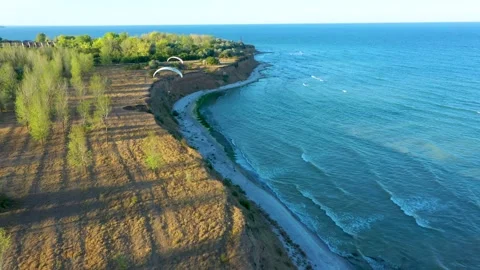Tracking Aerial View of Paragliding Pacarhute Flying Above the sea coastline Stock Footage 199823134