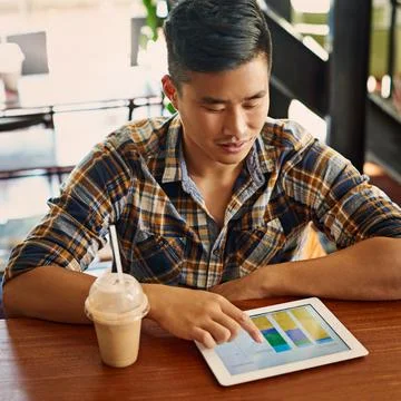Tracking all his progress online. a young designer using a digital tablet in an Stock Photos