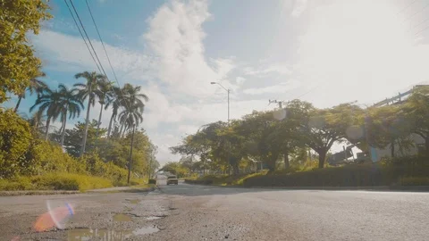 Tracking and panning shot of an old car driving along a sunny cuban road Stock Footage 88762846