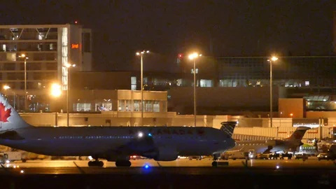 Tracking and panning shot of plane taxiing towards airport at night Video stock 127607848