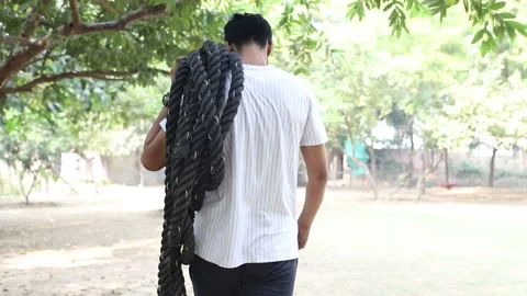 Tracking Back shot of Guy Going for exercise at home ground  with battle rope Video stock 144262008