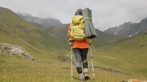 Tracking back view young woman hike use poles in scenic caucasus mountains .. Stock Footage 282973605