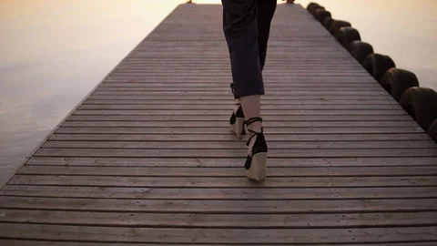 Tracking backside footage of a tall, long haired woman walking in black clothes Stock Footage 90746038