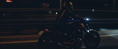 TRACKING Biker riding his custom built motorcycle through city at night Stock Footage 202090653
