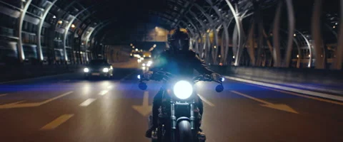 TRACKING Biker riding his custom built motorcycle through city at night Stock Footage 202092535