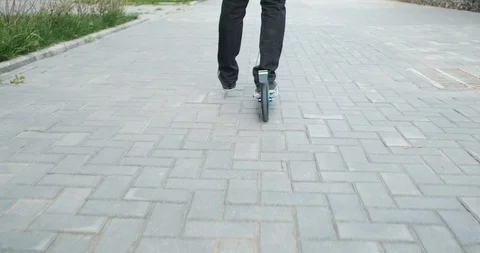 Tracking camera takes man riding scooter, view from back, summer nice weather Stock Footage 115938335