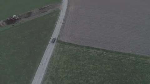 Tracking a car driving on a field road between meadow and soil field, 4K Stock Footage 74708356