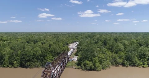 Tracking cargo train crossing large river into dense forest  drone aerial 4K Stock Footage 111364278