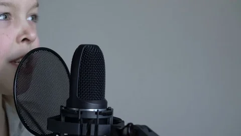Tracking close-up shot of Cute little blonde girl with headphones singing with a Stock Footage 75173336
