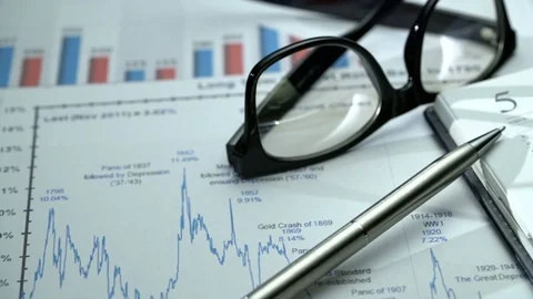 Tracking close-up shot of office desk with business graphics, glasses, pen and Video stock 75945070
