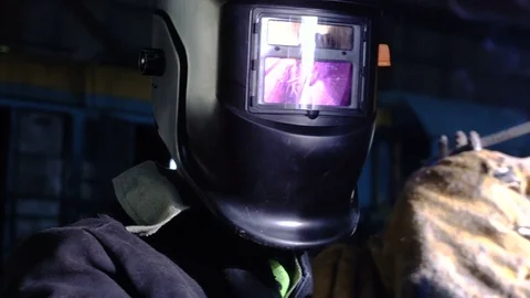 Tracking close-up of welder in the protactive mask welding the metal parts of Stock Footage 75344799