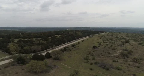 Tracking cyclist riding along back road with trees and grass drone aerial 4K Stock Footage 111361898