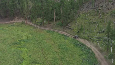 Tracking drone shot of a 4x4 UTV, ATV, driving and winding off-road through a Stock Footage 303064460