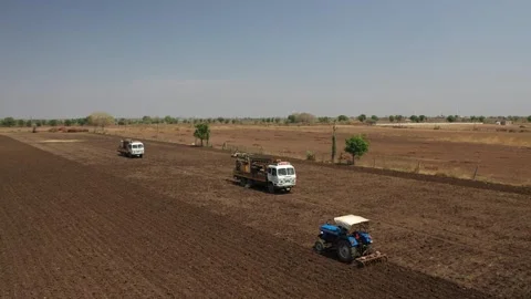 Tracking drone shot close to a blue industrial tractor pulling a tilled harrow Video stock 337195626