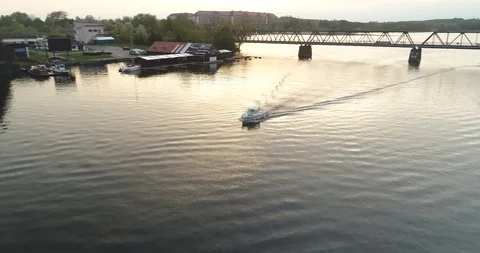 Tracking drone shot of a motorboat sailing under the bridge in port town. Stock Footage 89415997