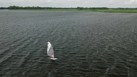 A tracking drone shot of multiple windsurfers on a lake Stock Footage 314665440