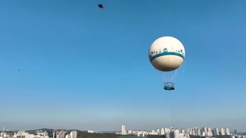 Tracking drone view of hot air balloon floating above city buildings Stock Footage 313465433