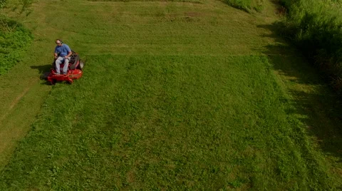 Tracking elevaated view of man on a riding lawn mower Vidéo 63216519