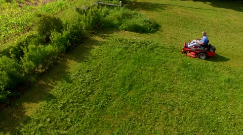 Tracking elevated view  of man on a riding lawn mower Vidéo 63216779