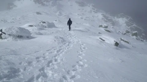Tracking of an explorer ascending to the mountain summit  Stock Footage 86614464