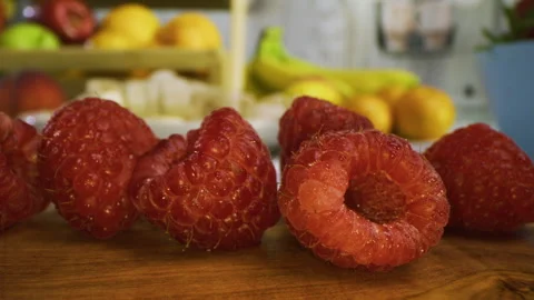 Tracking, extra closeup shot across tiny raspberries on cutting board in kitchen Vídeo Stock 341221553