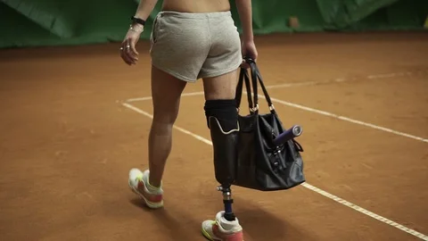 Tracking footage of a invalid athlete walking on the tennis court with the Stock Footage 89463682