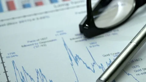 Tracking macro shot of office desk with business graphics, glasses, pen and Stock Footage 75944924
