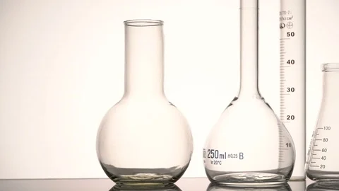 Tracking mid shot of empty chemical glass flasks and test tube reflecting on the Stock Footage 75940156