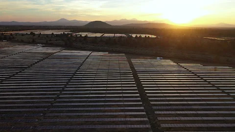 Tracking out over solar plant with cinematic sunset and mountains Stock Footage 160932031