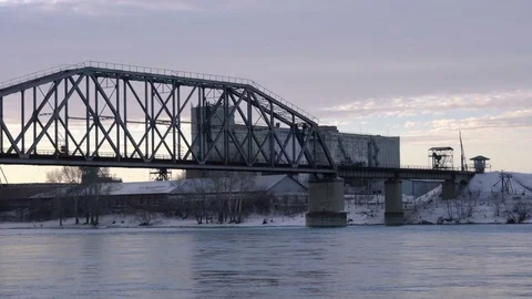 Tracking PAN of railway bridge over the river at dawn with industrial building Stock Footage 75288793
