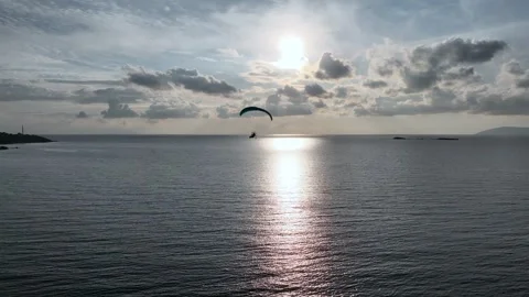 Tracking a paramotor flying in the air with a drone on a cloudy day Stock Footage 262523077
