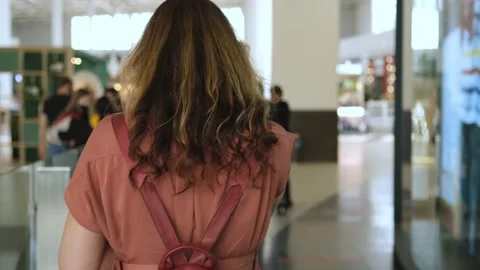 Tracking rear shot of slim young woman walking through mall Stock Footage 156228601
