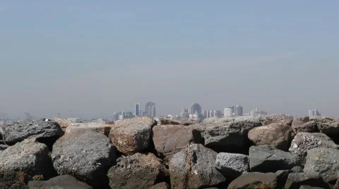 Tracking seagull along rock jetty with Long Beach skyline Stock Footage 68510432