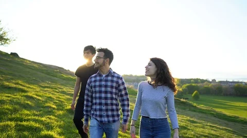 Tracking Shot of 3 Happy Young Adult Friends Walking Together in Nature With Sun Stock Footage 121197034