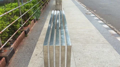 Tracking Shot Along Modern Stainless Steel Public Bench on Urban Sidewalk Stock Footage 342226126