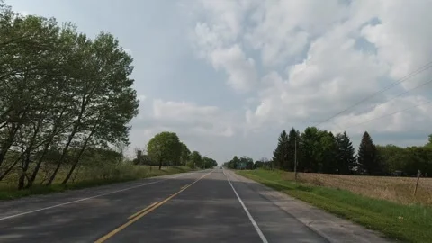 Tracking shot along rural two-lane highway under cloudy spring sky Stock Footage 321035508