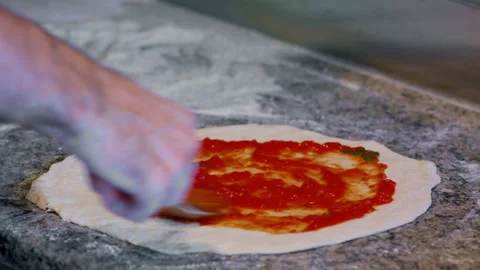 Tracking shot of applying tomato ketchup with metal spoon on pizza base. Video stock 159339415