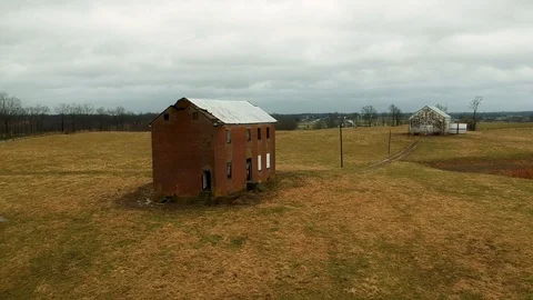 Tracking in shot of backside of old abandoned farmhouse in middle of pasture Stock Footage 100416568