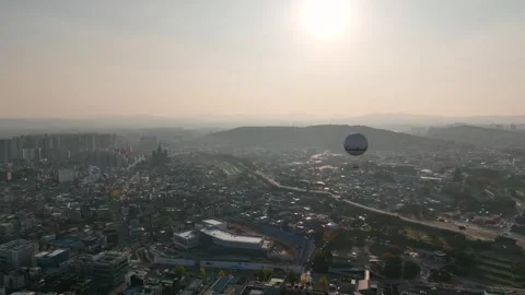 Tracking shot of balloon floating over sunset city skyline Stock Footage 313464994