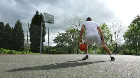 Tracking shot of a basketball player practicing dribbling and scoring Видео 37537932